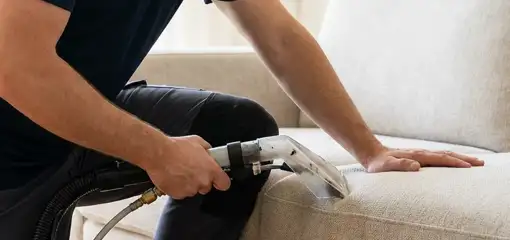 Professional upholstery cleaner deep-cleaning a fabric sofa with a handheld extraction tool, Syracuse, NY.